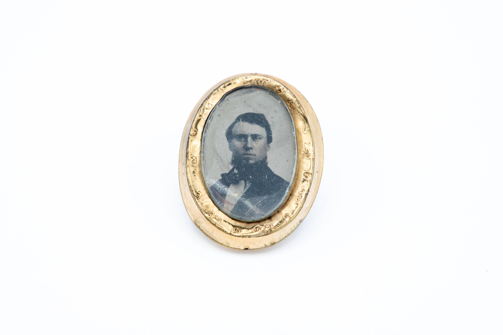 Front of a metal button with a black and white photograph of a man in it.